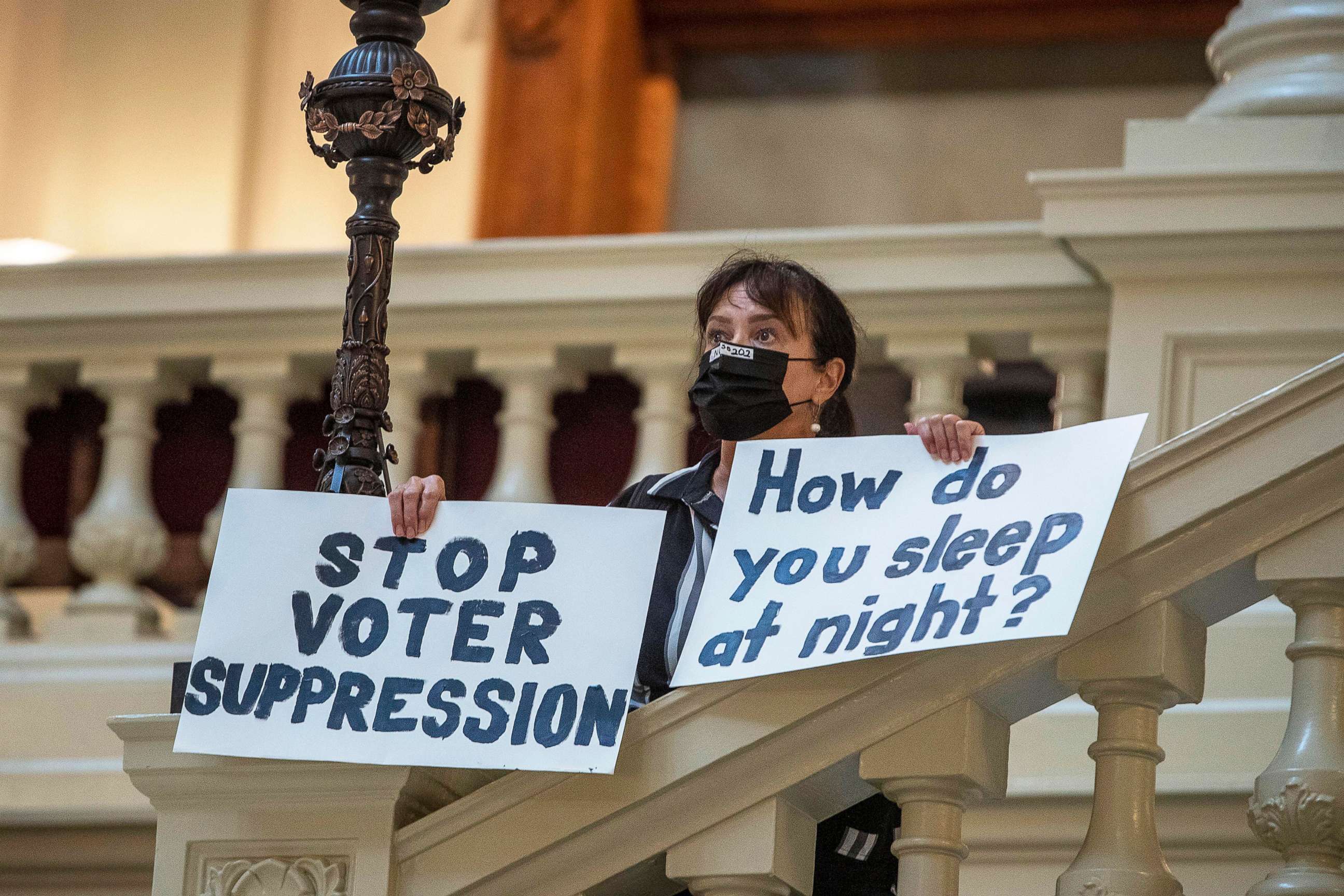 PHOTO: Ann White of Roswell holds protest signs on the North Wing stairs of the Georgia State Capitol building on day 38 of the legislative session in Atlanta, March 25, 2021. 