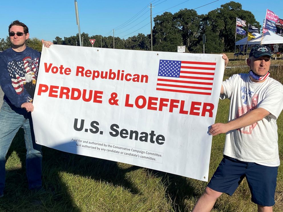 PHOTO: Two demonstrators hold a sign urging Trump supporters to vote for Republican U.S. Senators Kelly Loeffler and David Perdue in runoff elections in Valdosta, Ga., Dec.5, 2020.