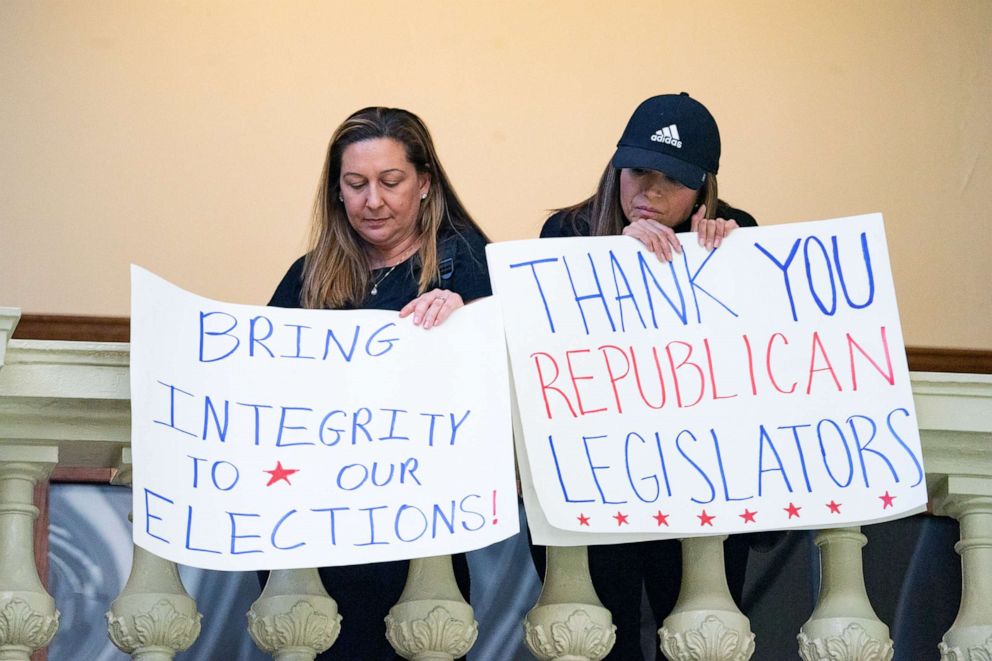 PHOTO: Supporters of House Bill 531 hold signs inside the Capitol building in Atlanta, March 8, 2021. HB531 restricts early voting hours, remove drop boxes, and require the use of a government ID when voting by mail.