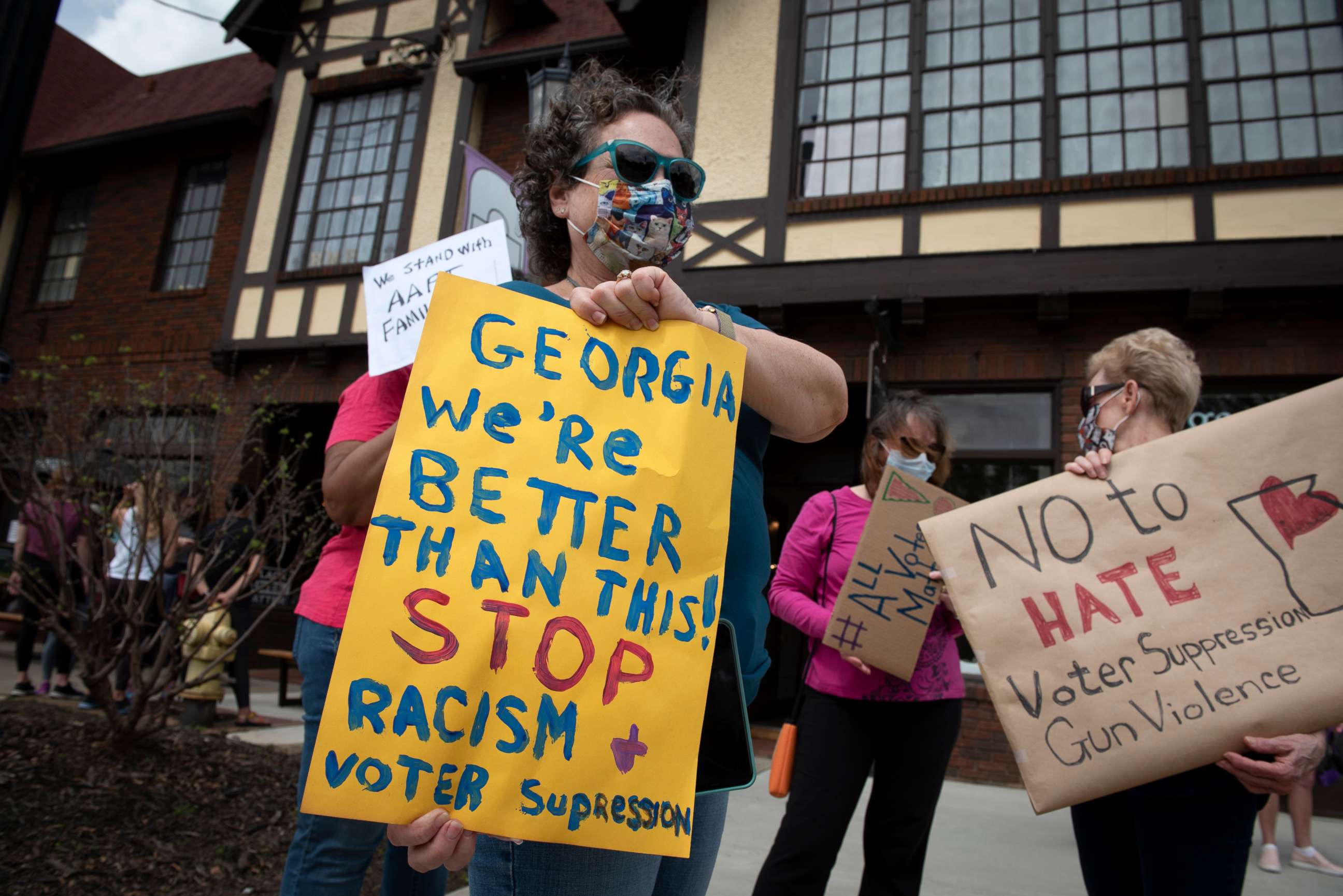 PHOTO: Protesters gather on a busy street corner to voice their opposition to the state's election laws, March 27, 2021, in Avondale Estates, Georgia.