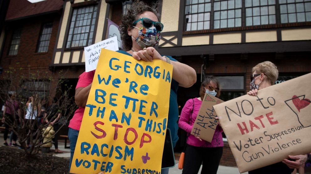 PHOTO: Protesters gather on a busy street corner to voice their opposition to the state's election laws, March 27, 2021, in Avondale Estates, Georgia.