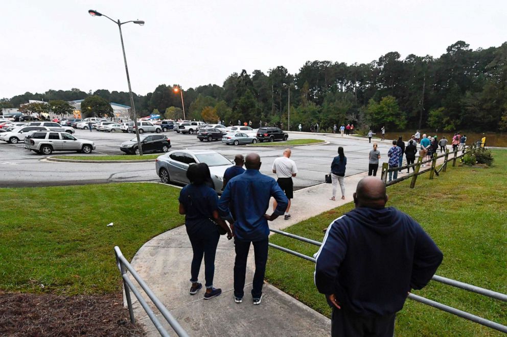 PHOTO: A line snakes through the parking lot as the first day of early voting gets underway at the Mountain Park Activity Building in Stone Mountain, Ga., Oct. 12, 2020.