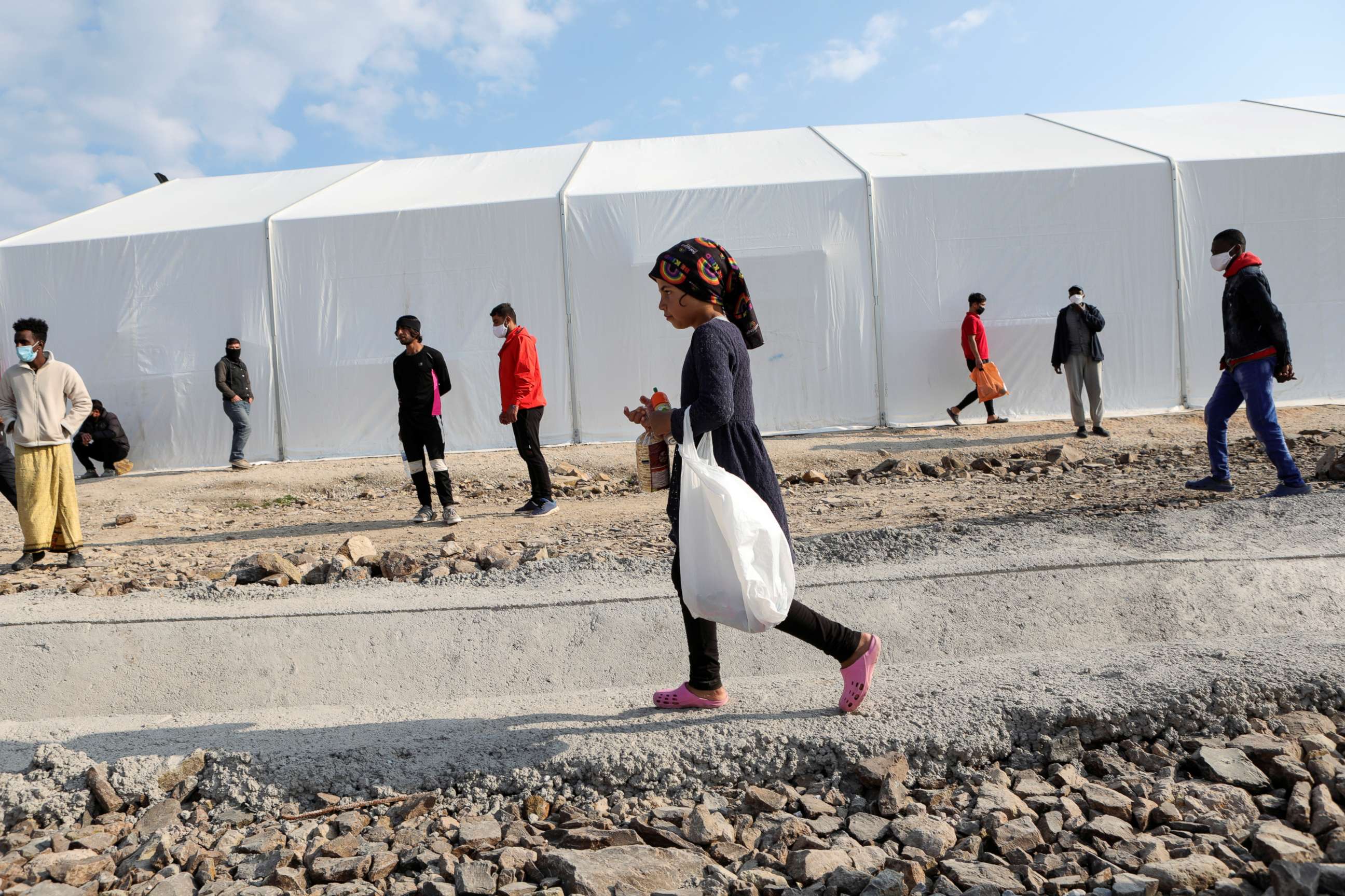 PHOTO: Refugees and migrants make their way in the Mavrovouni camp on the island of Lesbos, Greece, March 29, 2021.