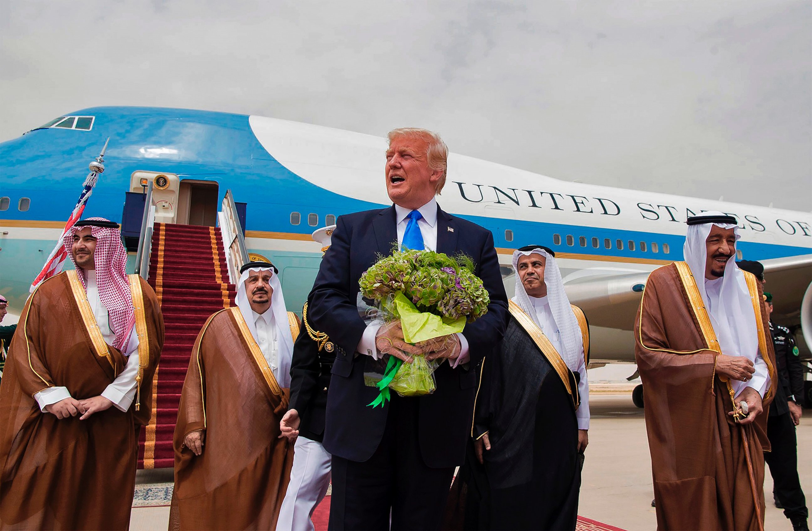 PHOTO: President Donald Trump holds a bouquet of flowers upon being welcomed by Saudi King Salman bin Abdulaziz al-Saud during his arrival at the airport in Riyadh on May 20, 2017.