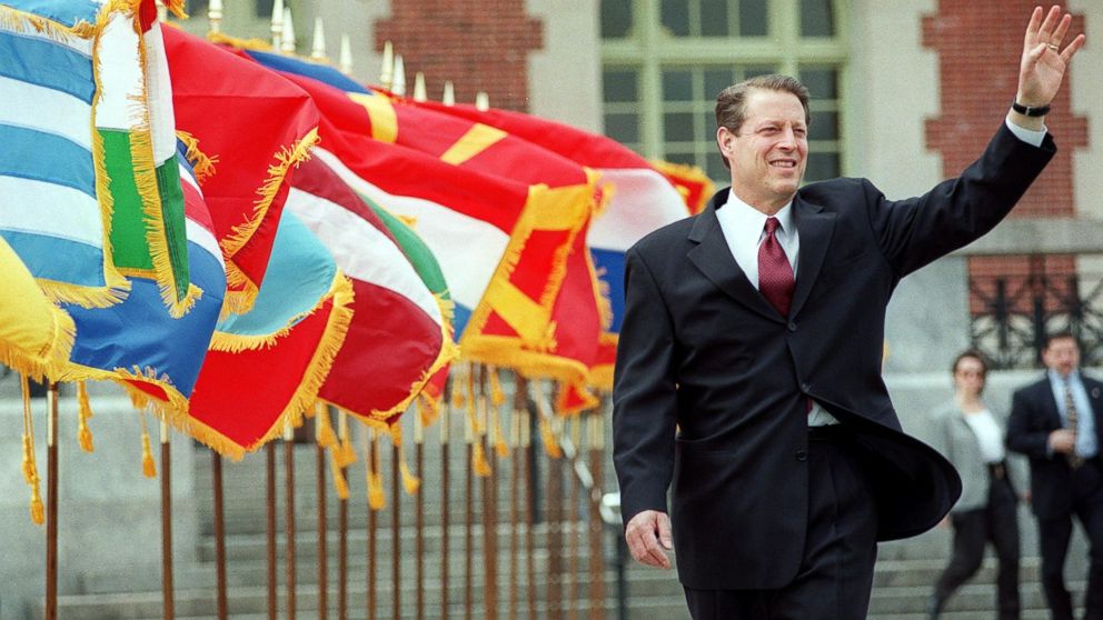 Al Gore waves as he walks past a row of flags at the start of the Commemoration Ceremony of the 50th Anniversary of the North Atlantic Treaty Organization in New York, April 21, 1999.