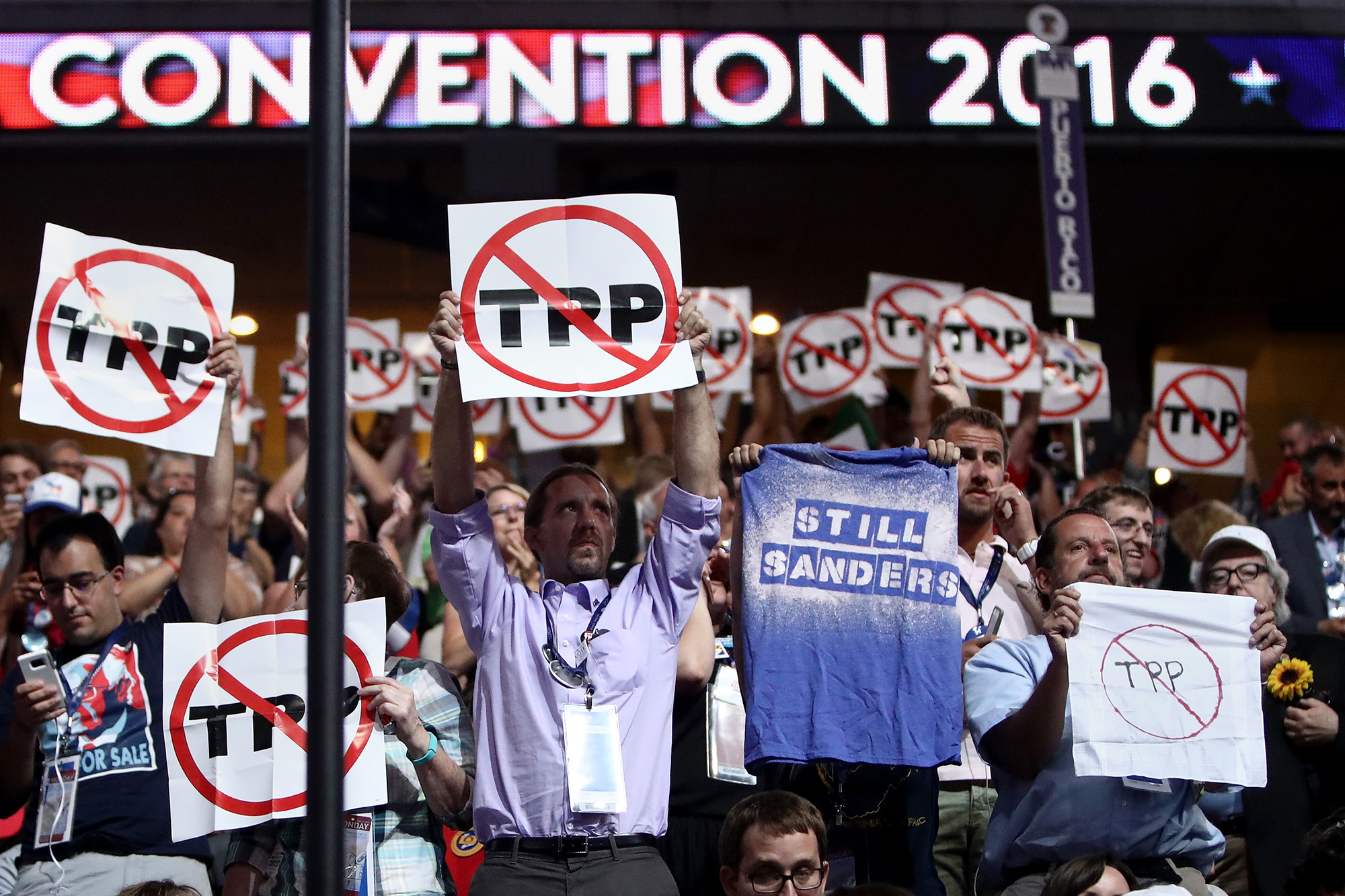PHOTO: Delegates hold up signs protesting the Trans-Pacific Partnership (TPP) on the first day of the Democratic National Convention at the Wells Fargo Center, July 25, 2016, in Philadelphia.