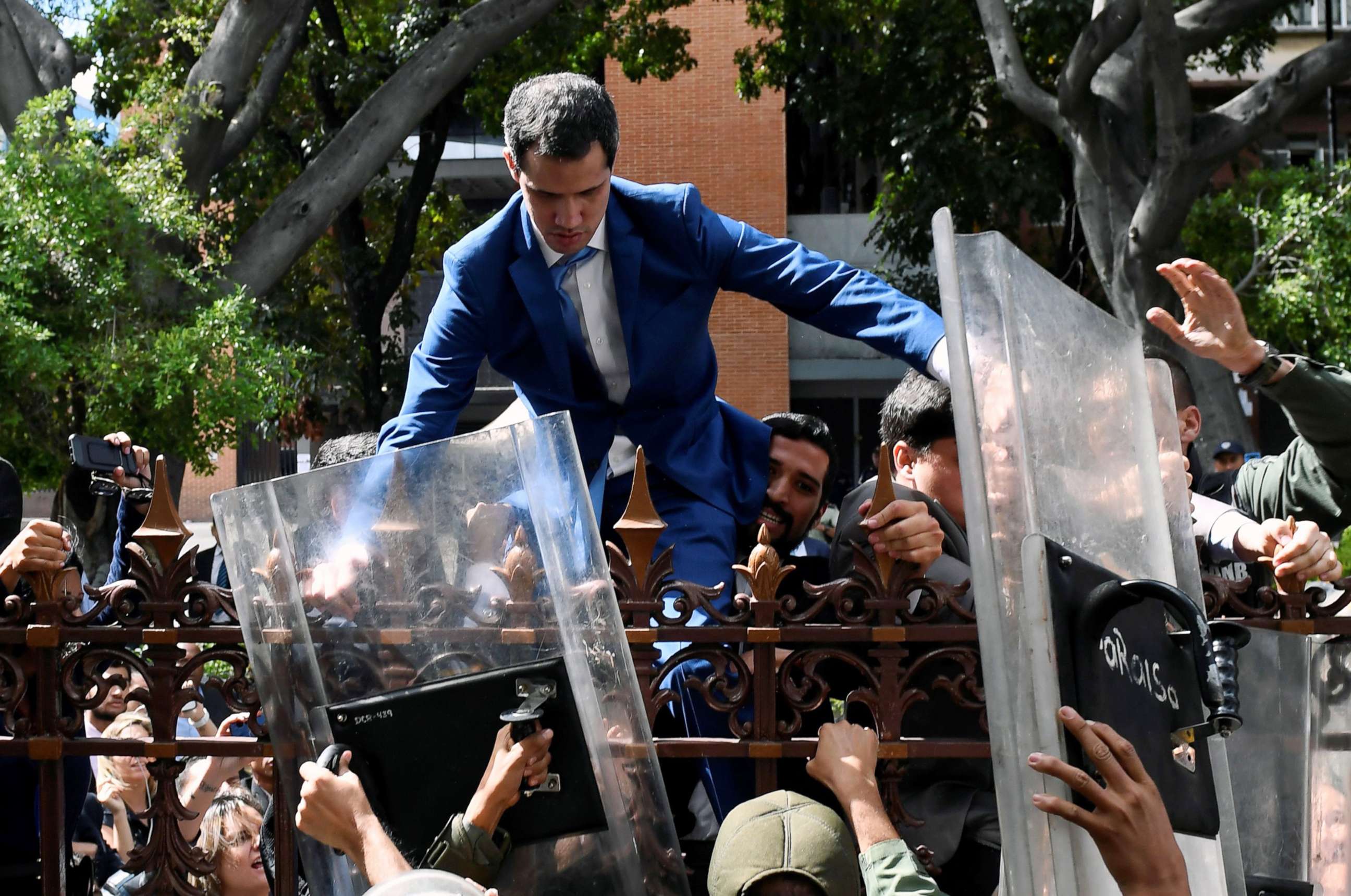 PHOTO: TVenezuelan opposition leader Juan Guaido is helped to climb a fence in an attempt to reach the National Assembly building in Caracas, on Jan. 5, 2020. Guaido and fellow opposition lawmakers were blocked from entering the National Assembly.