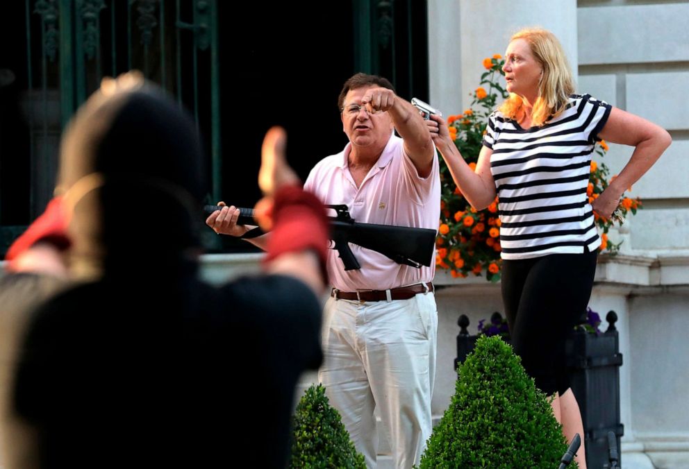 PHOTO: Armed homeowners Mark and Patricia McCloskey, standing in front their house along Portland Place confront protesters marching to St. Louis Mayor Lyda Krewson's house in St. Louis, June 28, 2020. 