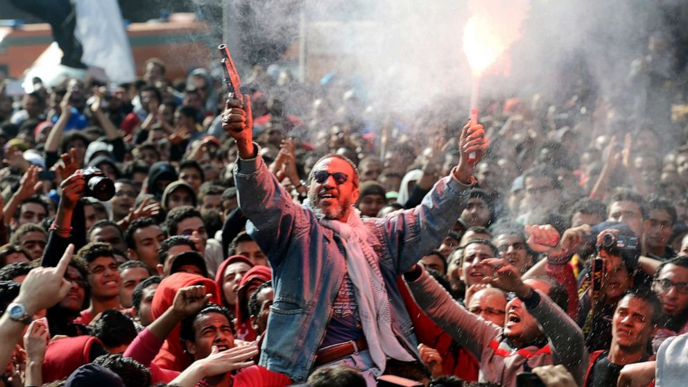 PHOTO: An Egyptian fan of Al-Ahly football club fires celebratory shots in the air and lights a flare as club supporters celebrate outside its headquarters in Cairo, Jan. 26, 2013.