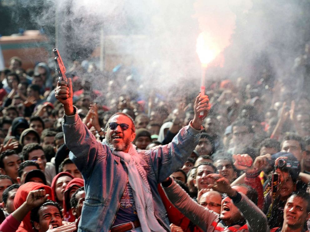 PHOTO: An Egyptian fan of Al-Ahly football club fires celebratory shots in the air and lights a flare as club supporters celebrate outside its headquarters in Cairo, Jan. 26, 2013.