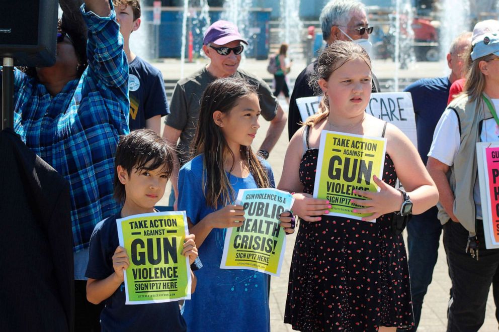 PHOTO: Children hold signs as backers of a proposed gun initiative deliver the signatures of thousands of voters to state election offices, on July 8, 2022, in Salem, Ore.