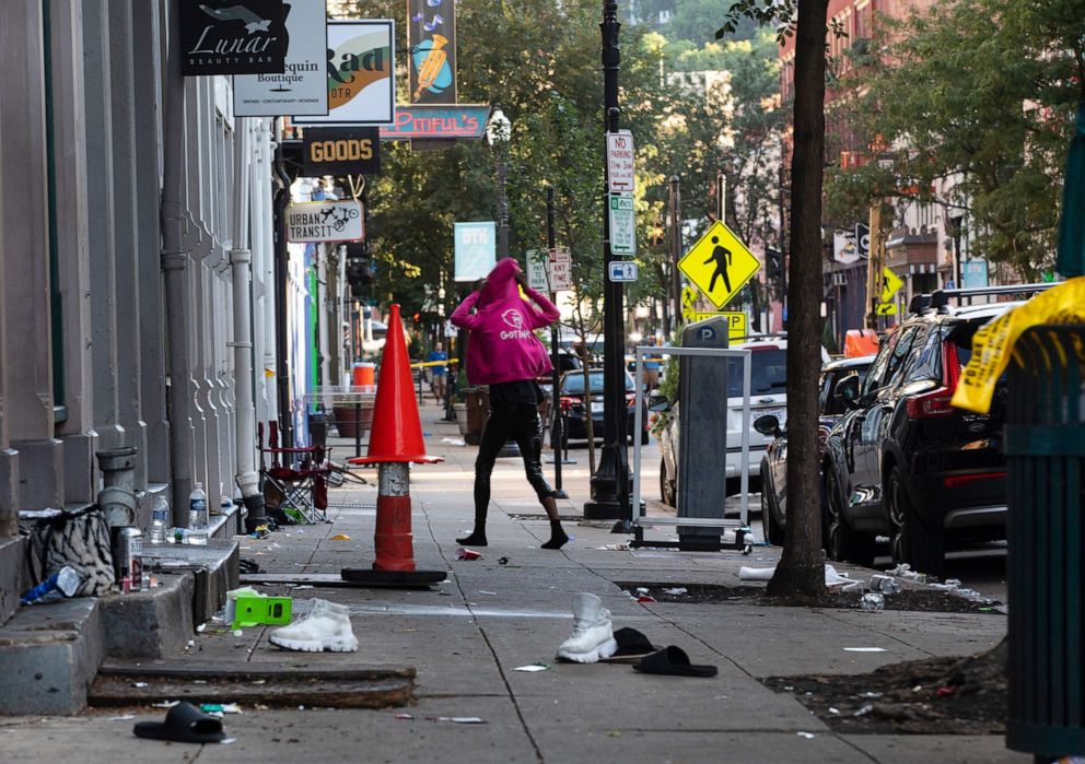 PHOTO: A woman looks for her shoes that were left at scene of a mass shooting is cordoned off by law enforcement in Over-the-Rhine, Cincinnati, Aug. 7, 2022.