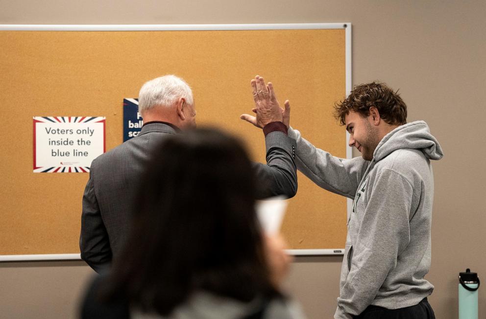 PHOTO: Democratic vice presidential nominee Minnesota Gov. Tim Walz, left, high-fives his son, Gus Walz, a first-time voter, as they cast their ballots during early voting at the Ramsey County Elections office in St. Paul, Minn., Wednesday, Oct. 23, 2024.