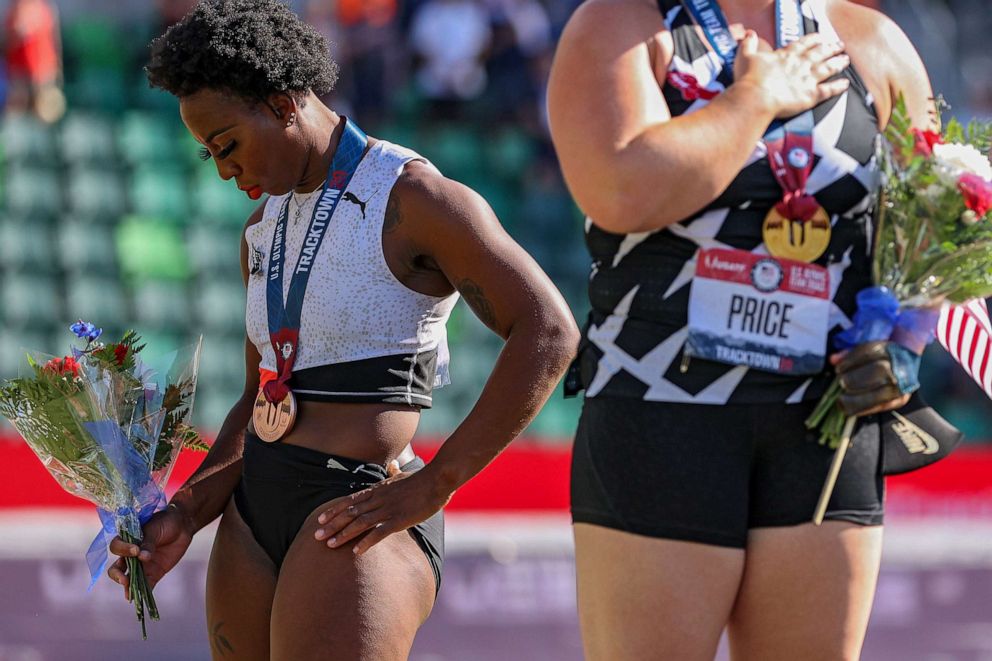 PHOTO: Gwendolyn Berry turns away from U.S. flag during the national anthem as DeAnna Price and Brooke Andersen stand on the podium after the Women's Hammer Throw final at the 2020 U.S. Olympic Track & Field Team Trials on June 26, 2021, in Eugene, Ore.
