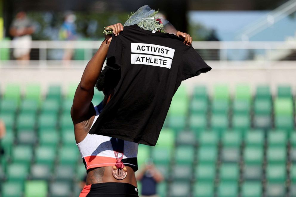 PHOTO: Gwendolyn Berry holds up a shirt that reads "Activist Athlete" as she celebrates finishing third in the Women's Hammer Throw final at the 2020 U.S. Olympic Track & Field Team Trials at Hayward Field on June 26, 2021, in Eugene, Ore.