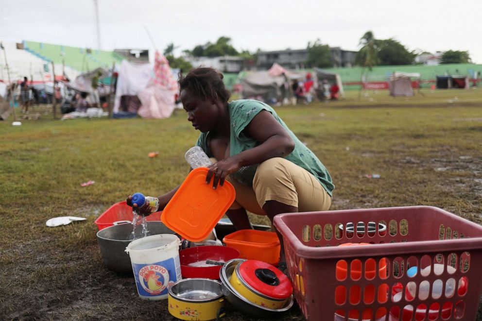 PHOTO: A woman washes kitchen utensils at a stadium used as shelter for residents who were evacuated from their damaged homes after Saturday's 7.2 magnitude quake, in Les Cayes, Haiti, Aug. 18, 2021.