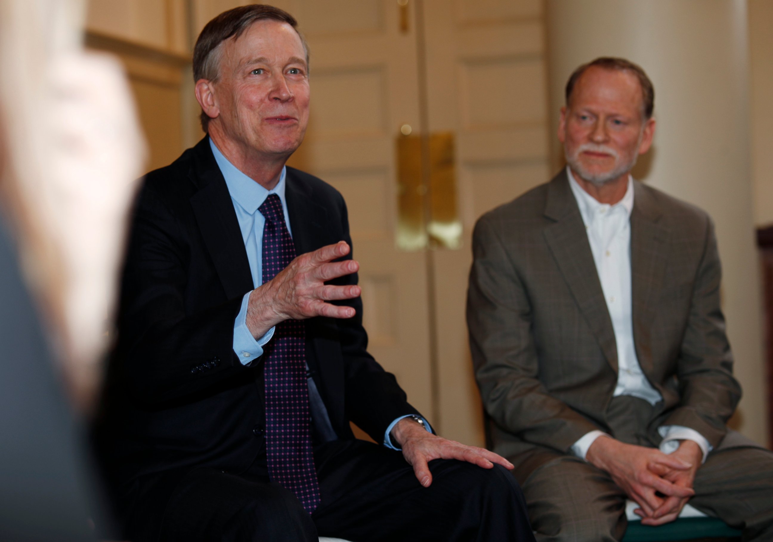 PHOTO: Democratic presidential hopeful John Hickenlooper, left, speaks as Michael Davis, back, looks on during a meeting with survivors of victims of mass shootings in Colorado Tuesday, April 16, 2019, in Denver.