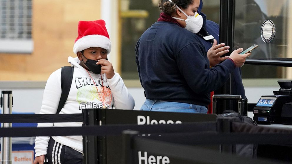 PHOTO: A young passenge pulls their face mask up while going through a security checkpoint at Ronald Reagan Washington National Airport, in Arlington, Va., Dec. 22, 2020.