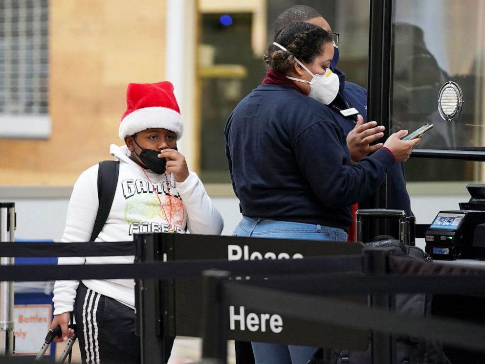 PHOTO: A young passenge pulls their face mask up while going through a security checkpoint at Ronald Reagan Washington National Airport, in Arlington, Va., Dec. 22, 2020.
