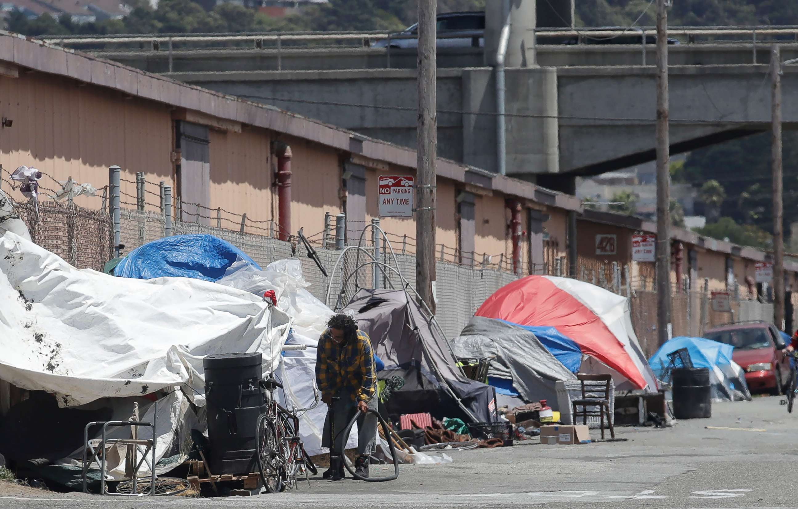 PHOTO: This Thursday, June 27, 2019, file photo shows a man holding a bicycle tire outside of a tent along a street in San Francisco.