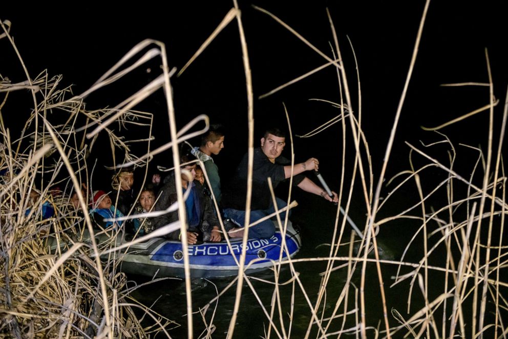 PHOTO: A group of immigrants from Honduras and Guatemala arriving illegally from Mexico ride in an inflatable boat steered towards the US side of the Rio Grande, Roma, Texas, March 28, 2021.