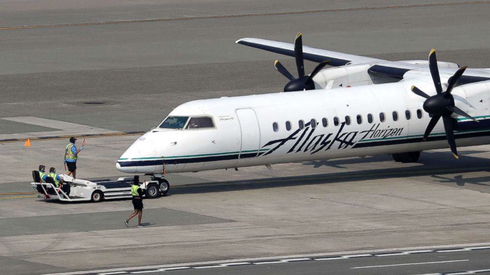 PHOTO: A Horizon Air Q400 turboprop airplane, part of Alaska Air Group, is moved into position by airport workers at Seattle-Tacoma International Airport in SeaTac, Wash., Aug. 13, 2018.