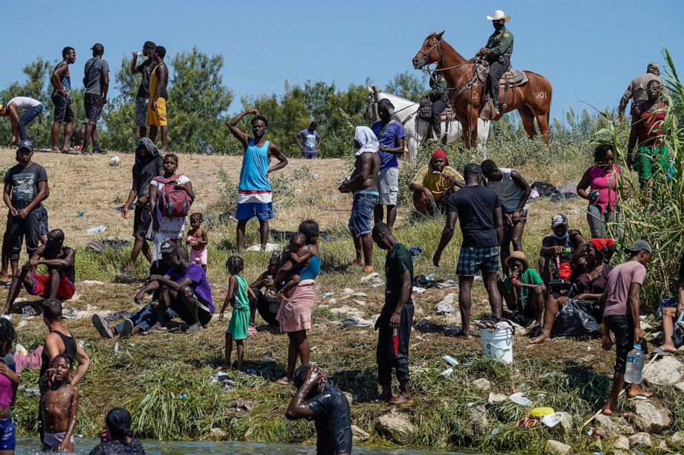 PHOTO: A United States Border Patrol agents on horseback look on as Haitian migrants sit on the river bank near an encampment on the banks of the Rio Grande near the Acuna Del Rio International Bridge in Del Rio, Texas, Sept. 19, 2021. 