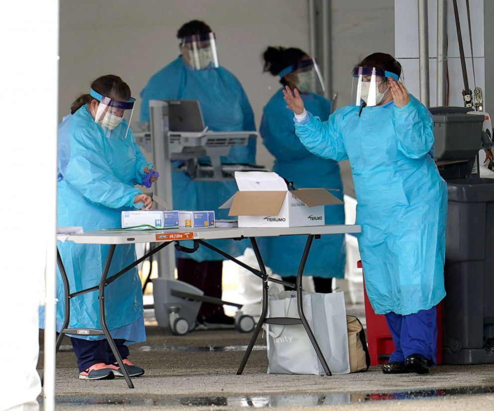 PHOTO: Medical professionals put on new gloves after washing their hands at a newly opened drive-thru testing site for COVID-19, March 20, 2020, in Houston. 