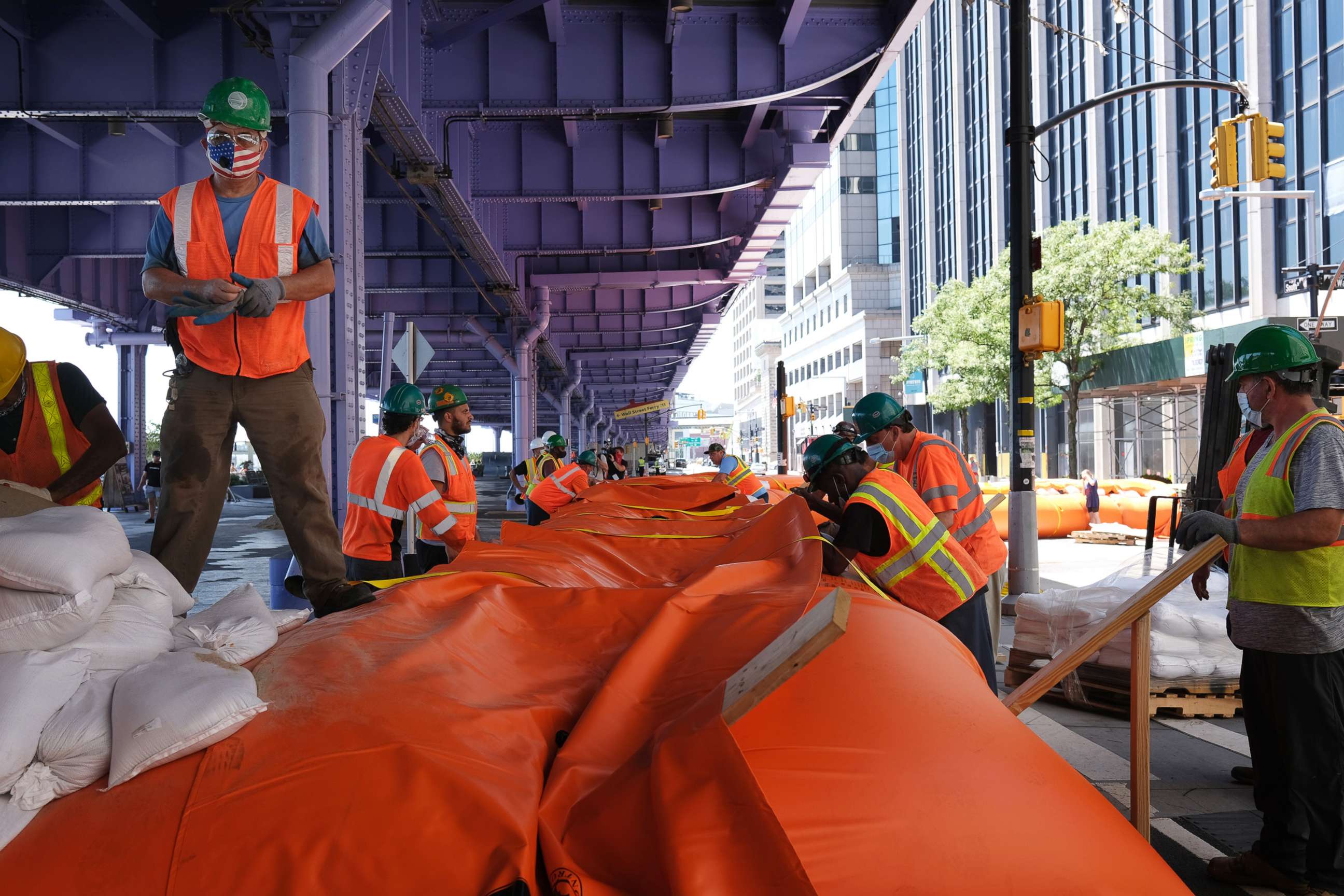 PHOTO: Workers erect temporary flood barriers in the South Street Seaport neighborhood in preparation for potential flooding and a storm surge from Tropical Storm Isaias, Aug. 3, 2020, in New York.