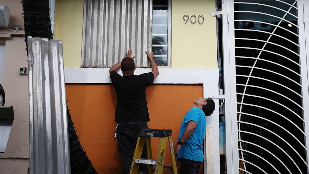 PHOTO: Workers place hurricane shutters over a window as they help prepare a business for the possible arrival of Hurricane Dorian on Aug. 30, 2019, in Miami Beach, Fla.