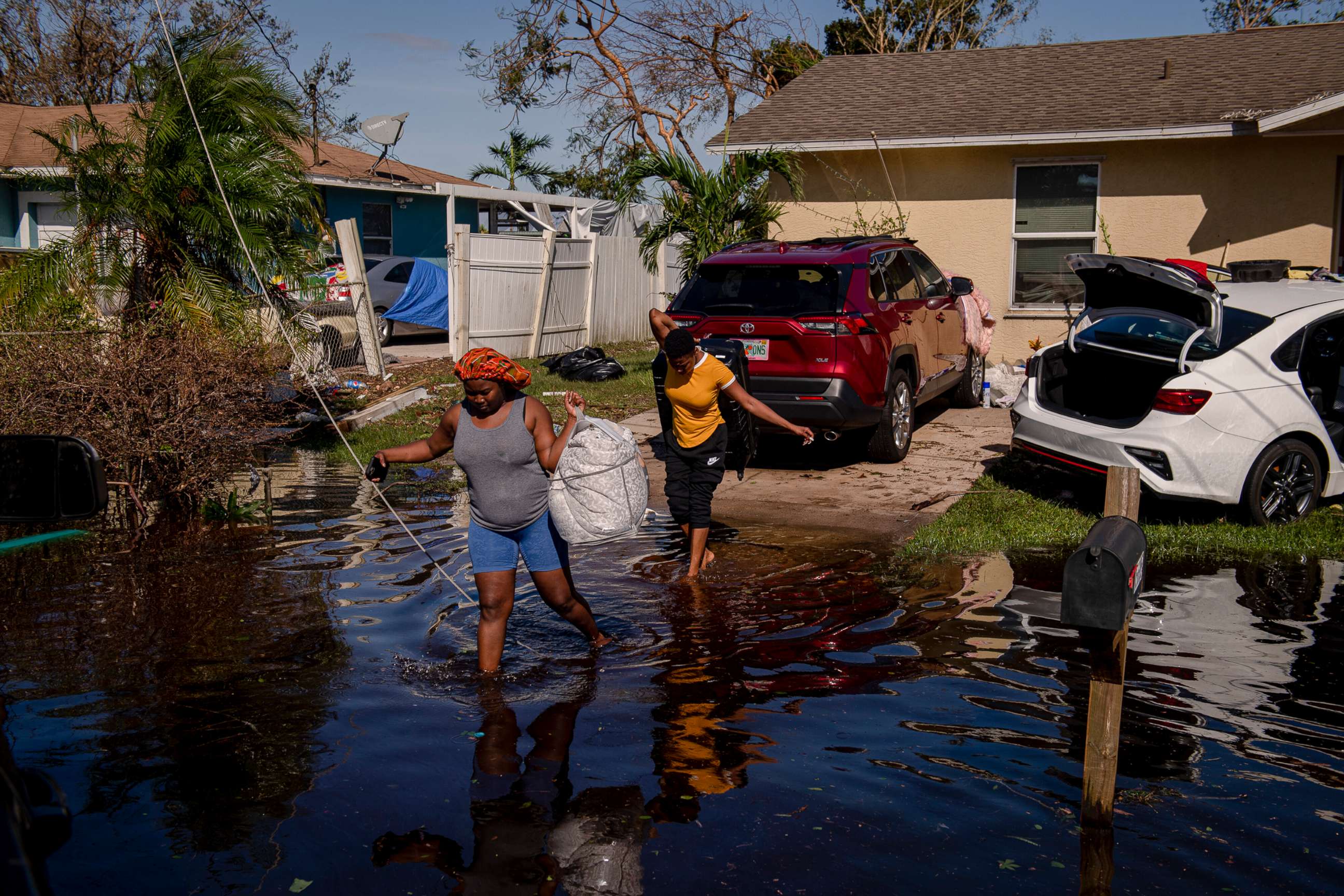 PHOTO: Atlas Dorlean, left, carries a bag of salvaged belongings through floodwater left after Hurricane Ian tore through the Harlem Heights area of Fort Myers, Fla. Sept. 29, 2022.