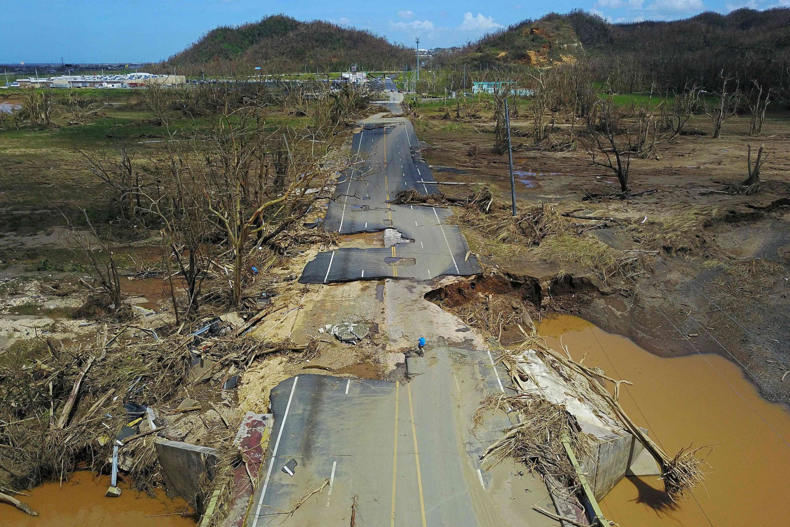 PHOTO: A man rides his bicycle through a damaged road in Toa Alta, west of San Juan, Puerto Rico, Sept. 24, 2017, following the passage of Hurricane Maria.