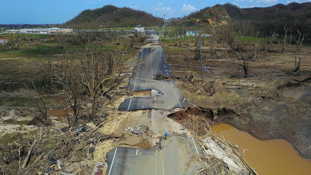 PHOTO: A man rides his bicycle through a damaged road in Toa Alta, west of San Juan, Puerto Rico, Sept. 24, 2017, following the passage of Hurricane Maria.