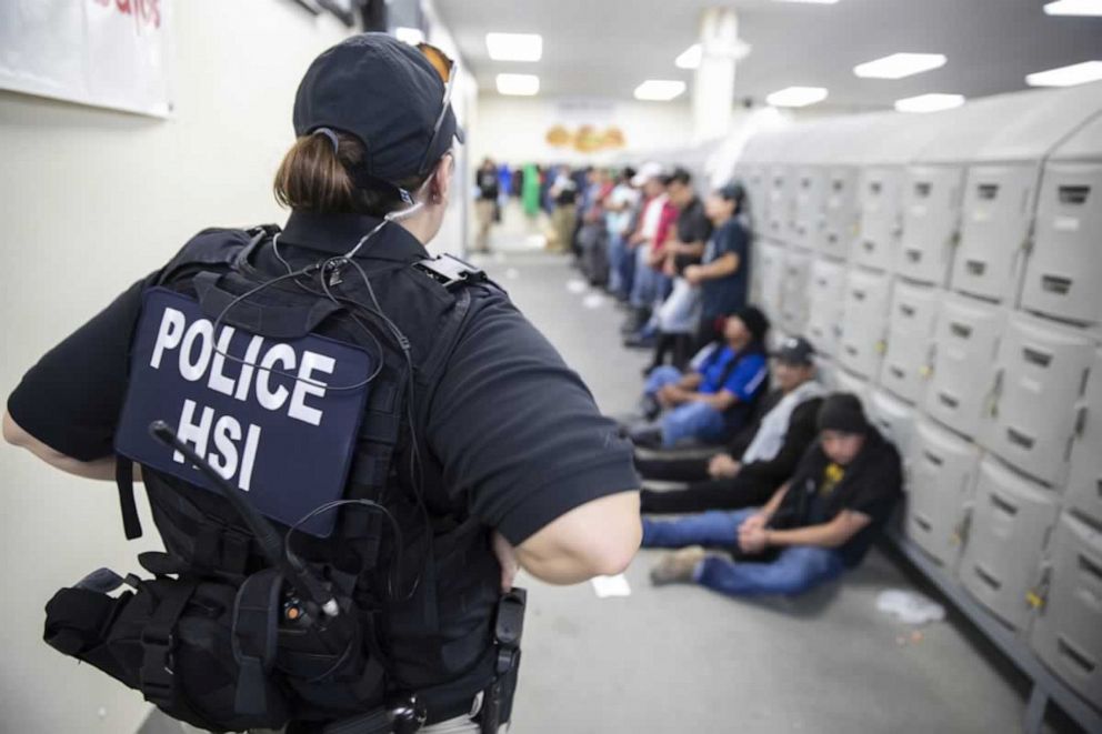 PHOTO: This image released by the US Immigration and Customs Enforcement (ICE) shows a Homeland Security Investigations (HSI) officer guarding suspected illegal aliens on August 7, 2019.