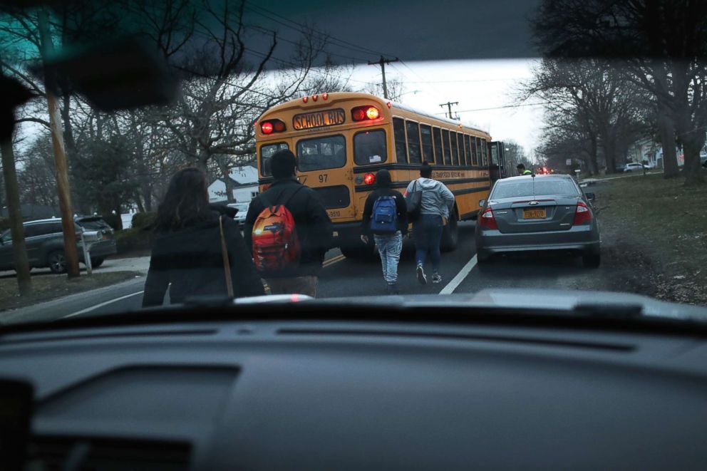 PHOTO: Students head to a school bus as Homeland Security Investigations (HSI) ICE agents prepare to arrest a fellow student and suspected MS-13 gang member at a nearby home, March 29, 2018 in Brentwood, New York.