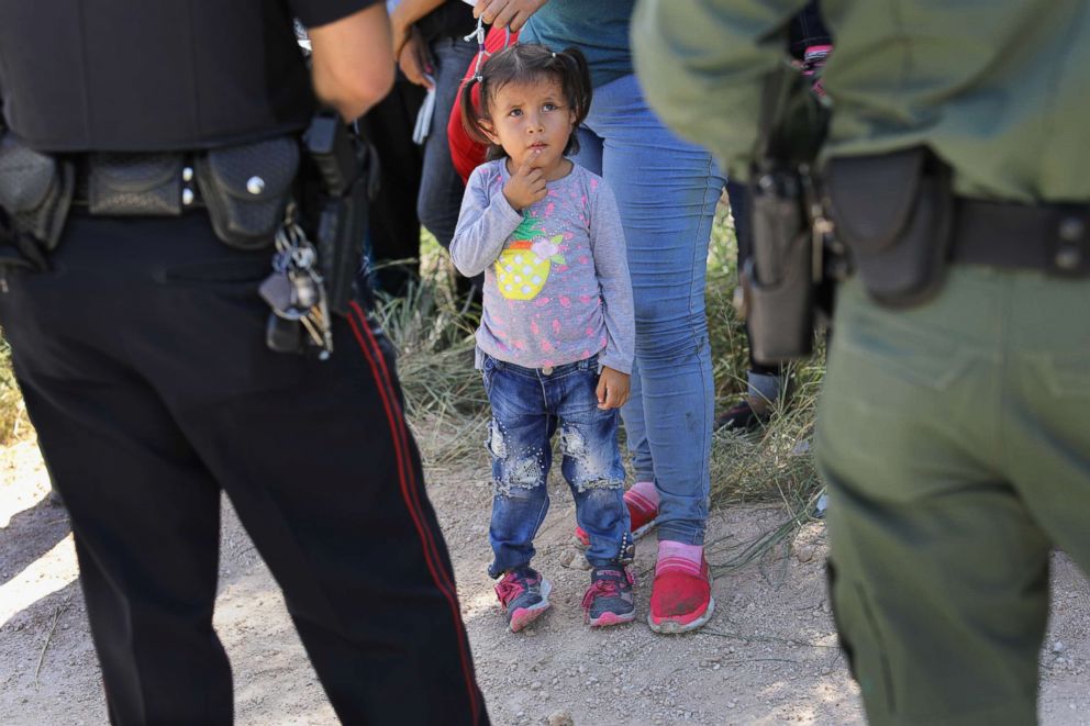 PHOTO: A Mission Police Dept. officer and a U.S. Border Patrol agent watch over a group of Central American asylum seekers before taking them into custody, June 12, 2018, near McAllen, Texas.