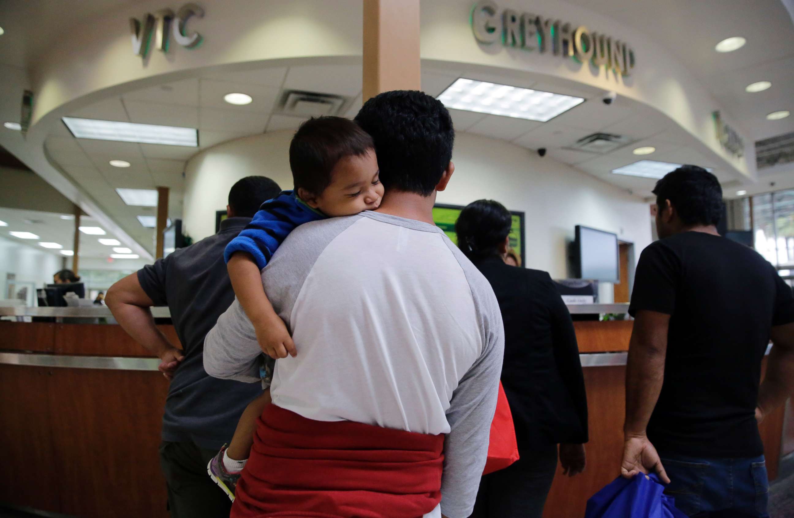 PHOTO: A group of immigrants from Honduras and Guatemala seeking asylum stand in line at the bus station after they were processed and released by U.S. Customs and Border Protection, June 21, 2018, in McAllen, Texas.