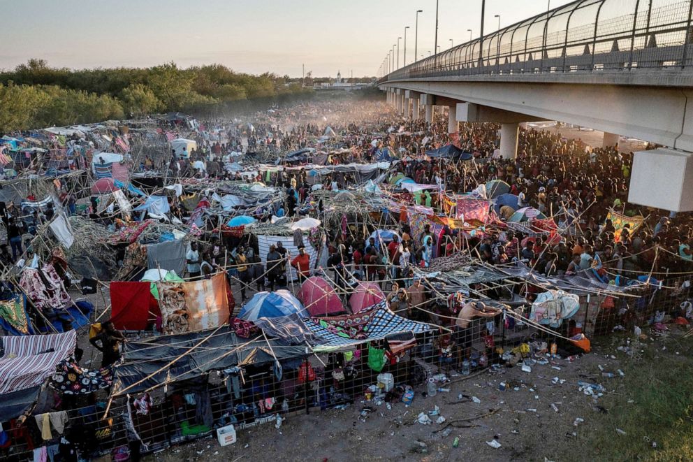 PHOTO: Migrants take shelter along the Del Rio International Bridge at sunset as they await to be processed after crossing the Rio Grande river into the U.S. from Ciudad Acuna in Del Rio, Texas, Sept. 19, 2021.