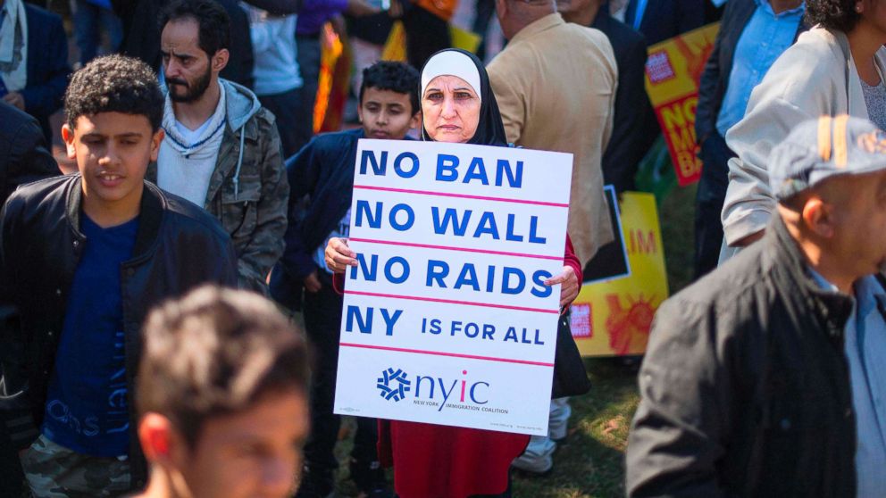A demonstrator holds up a placard as other pass by during a #NoMuslimBanEver rally and march "to protest discriminatory policies that unlawfully target and hurt American Muslim and immigrant communities across the country" in Washington, D.C., Oct. 18, 2017.

