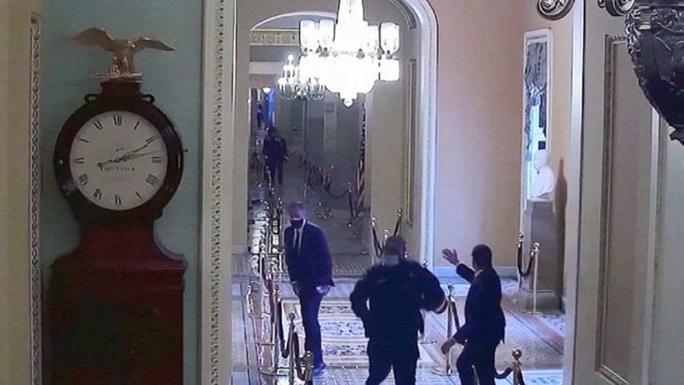 PHOTO: Capitol Police officer Eugene Goodman runs past Sen. Mitt Romney, in security footage from the security breach of the Capitol on Jan. 6, 2021.