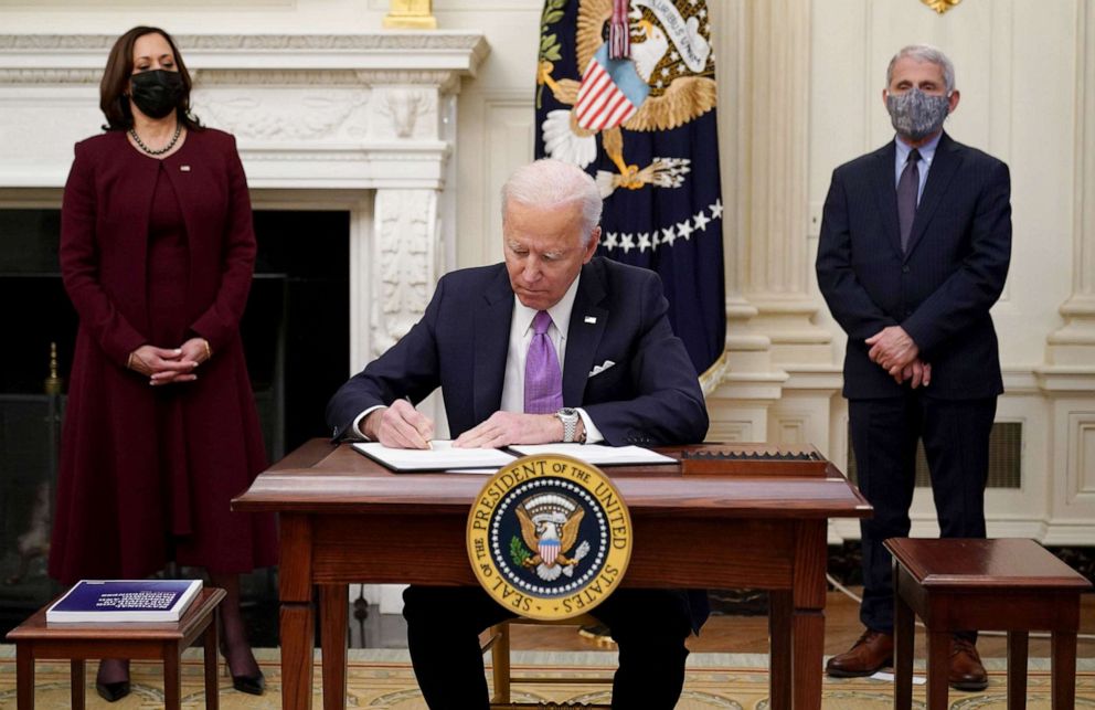 PHOTO: President Joe Biden signs executive orders as part of the Covid-19 response as US Vice President Kamala Harris and Director of NIAID Anthony Fauci look on in the State Dining Room of the White House, on Jan. 21, 2021.