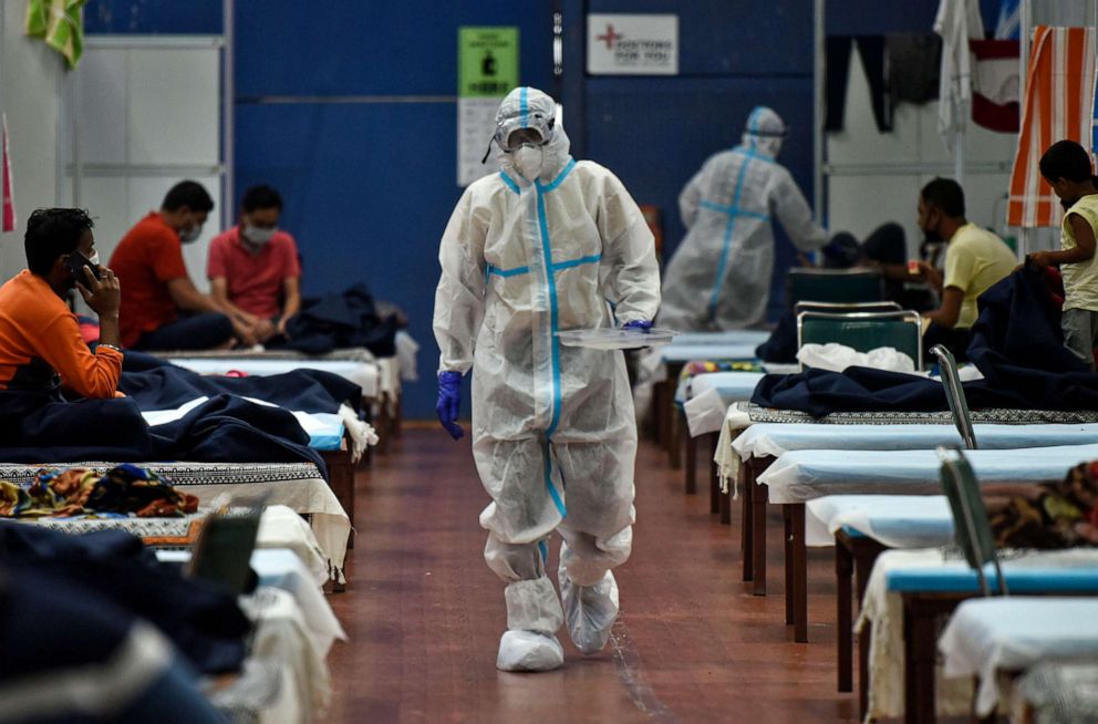 PHOTO: A health worker serves food to COVID-19 patients housed at the Commonwealth Games Village Sports Complex which is a temporary coronavirus care center, at Patparganj, on July 12, 2020 in New Delhi, India.