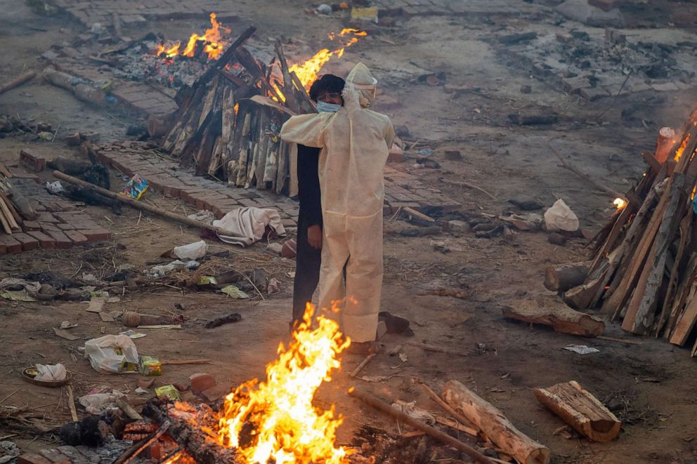 PHOTO: Family members embrace each other amid burning pyres of victims who lost their lives due to the Covid-19 coronavirus at a cremation ground in New Delhi on April 26, 2021.