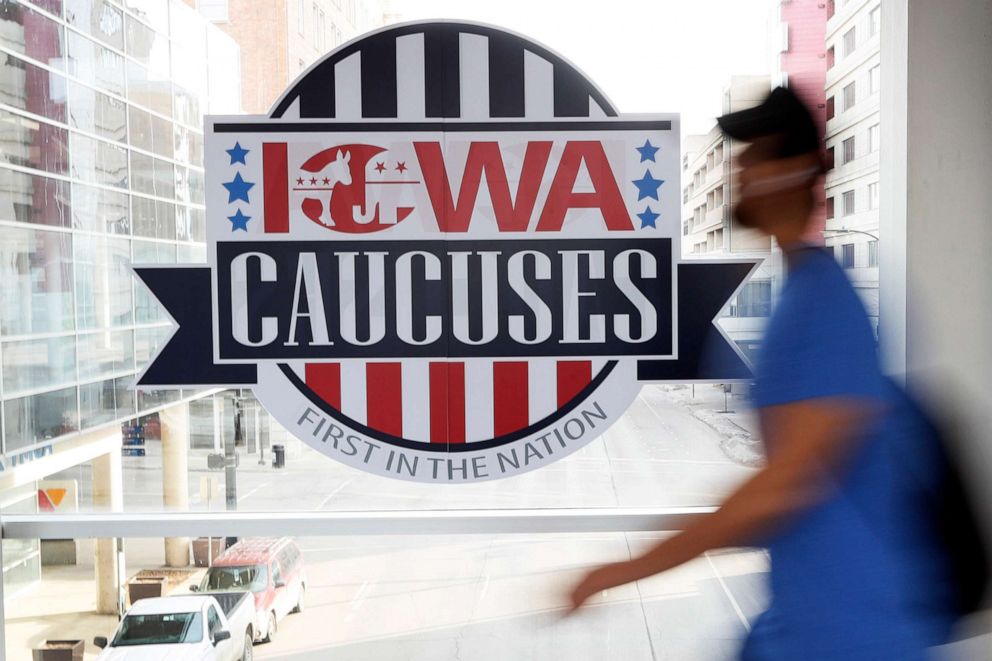 PHOTO: A pedestrian walks past a sign for the Iowa Caucuses on a downtown skywalk, in Des Moines, Iowa, Feb. 4, 2020. 