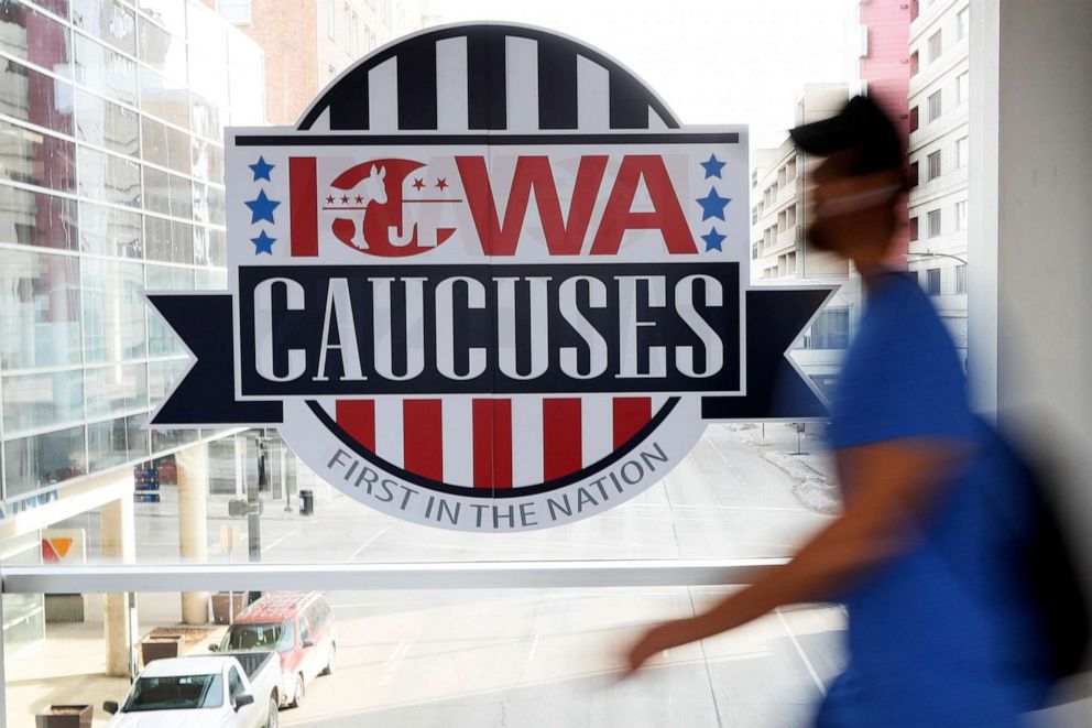 PHOTO: A pedestrian walks past a sign for the Iowa Caucuses on a downtown skywalk, in Des Moines, Iowa, Feb. 4, 2020.