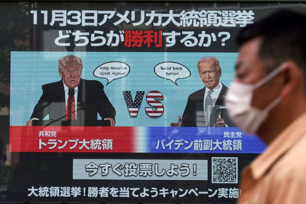 PHOTO: A man walks past a screen showing Republican President Donald Trump, left, and Democratic candidate and former Vice President Joe Biden for an online voting to predict the winner in the U.S. presidential election, in Tokyo, Oct. 26, 2020.