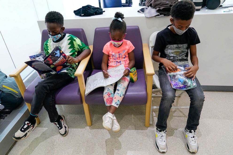PHOTO: Siblings Amechi, 7, left, Chizara, 5, center and Kenechi Acholonu, 9, wait in the observation area after receiving the first dose of the Pfizer COVID-19 vaccine for children 5 to 11 years at a hospital in New York City.