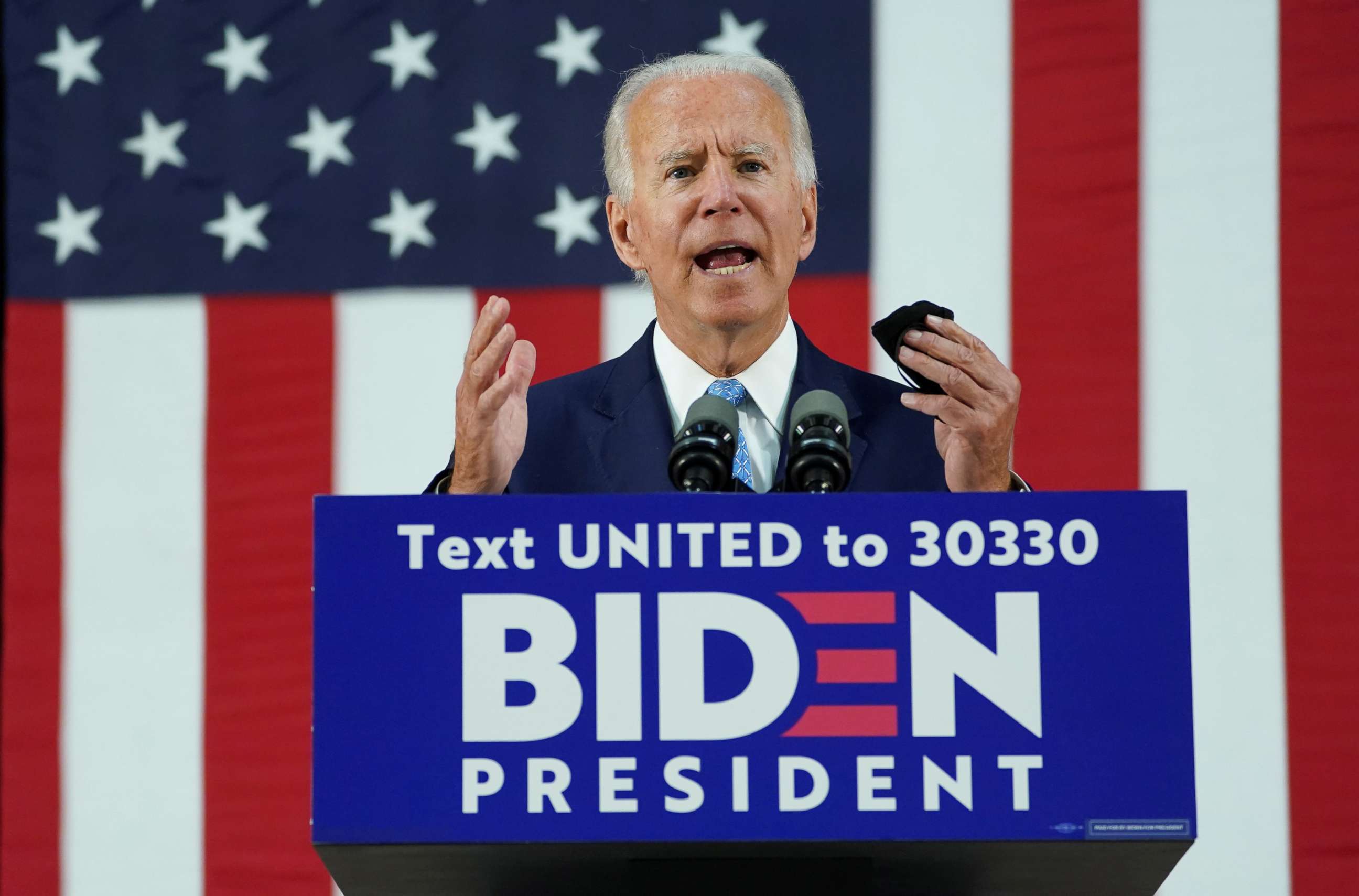 PHOTO: Former Vice President Joe Biden holds his protective face mask as he speaks about the Trump administration's handling of the coronavirus pandemic during a campaign event in Wilmington, Del., June 30, 2020.