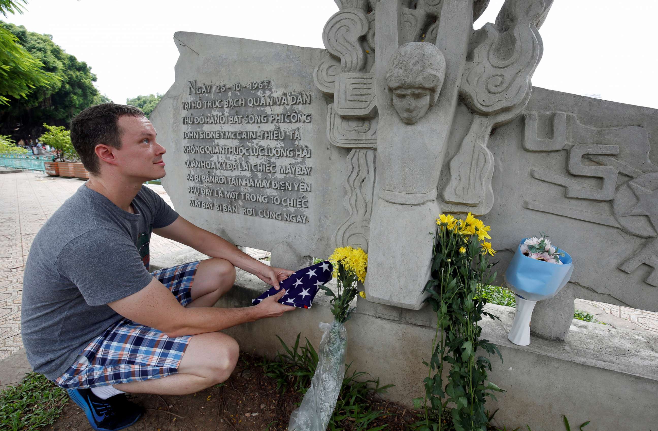PHOTO: English teacher Derek Davis from the U.S. places an American flag and flowers in memory of the late Senator John McCain at the McCain Memorial in Hanoi, Vietnam, Aug. 26, 2018.