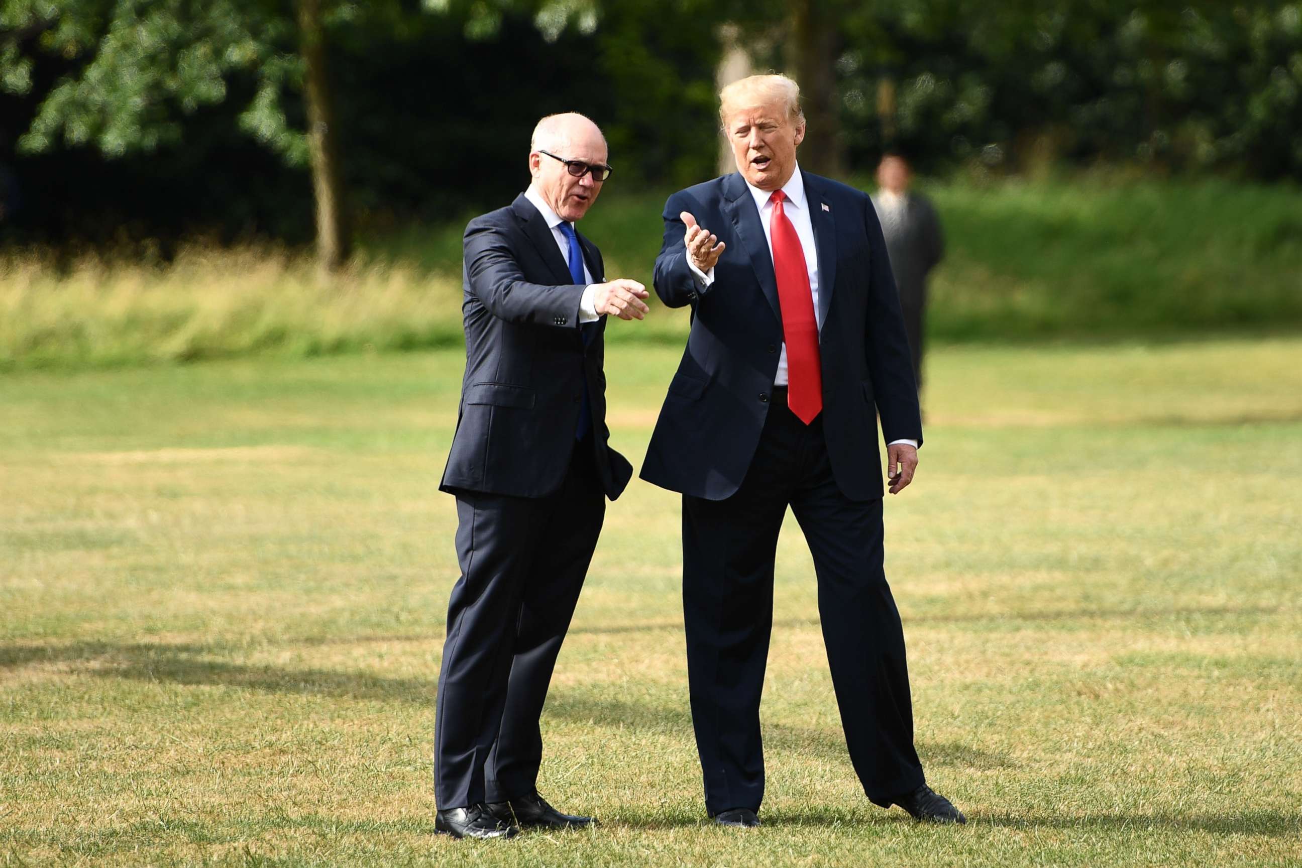 PHOTO: US President Donald Trump gestures as he talks with US Ambassador to the United Kingdom Woody Johnson preparing to board Marine One to depart the US ambassador's residence Winfield House in London on July 13, 2018.